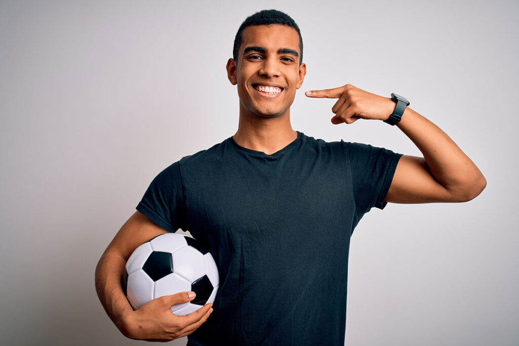 Sports dentistry - soccer player pointing at teeth
